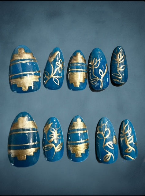 Blue nail art with gold shimmer designs on a blue background